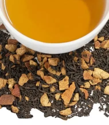 Photo coupée en deux : Copeaux de Thé noir Hot Cinnamon Sunset Harney and Sons en bas et demie tasse remplie de thé en haut